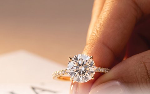 Round brilliant pavé ring held between fingers above a diamond grading document.