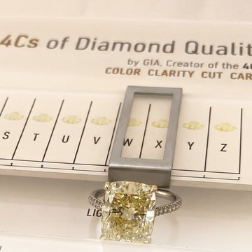 Warm-toned rectangular diamond ring on a color comparison chart.