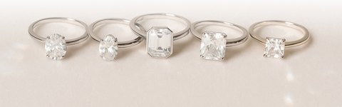 Five engagement rings showing oval, round, emerald, cushion, and princess-shaped diamonds.